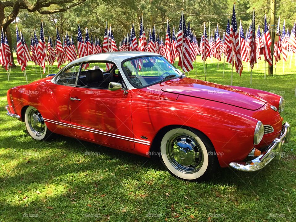 Red Karmann Ghia with red, white and blue American flag backdrop.  Visually, red is a color that commands attention. It provokes an emotional response.