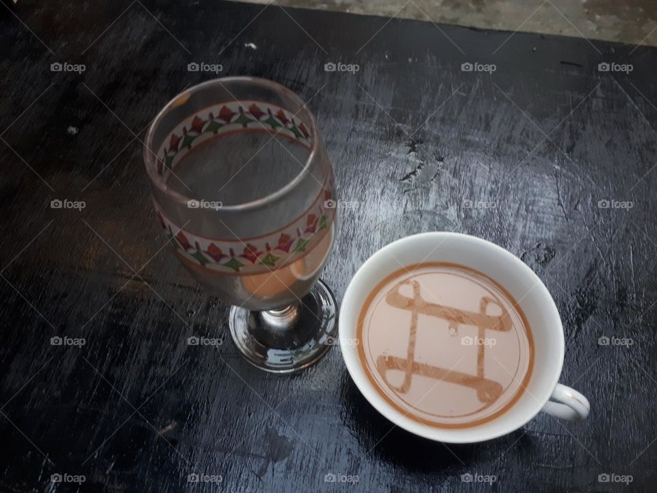 Artistic design of how to pour mocha coffee between 2 glasses on a black wooden table