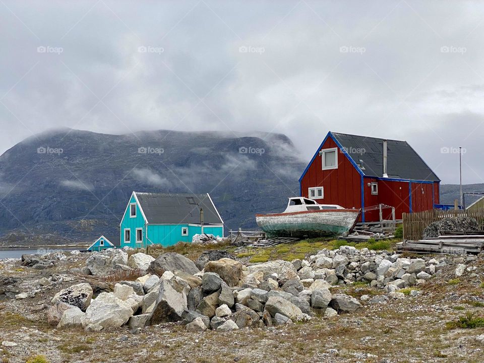 Two brightly colored houses and a boat in a village in Greenland 