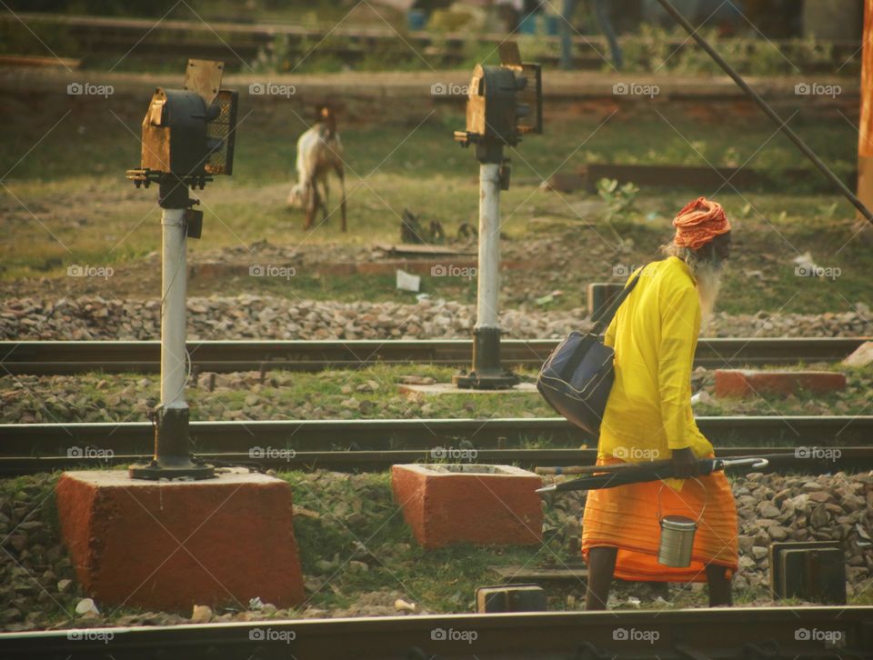 A man in bright clothing walking along the railway tracks.