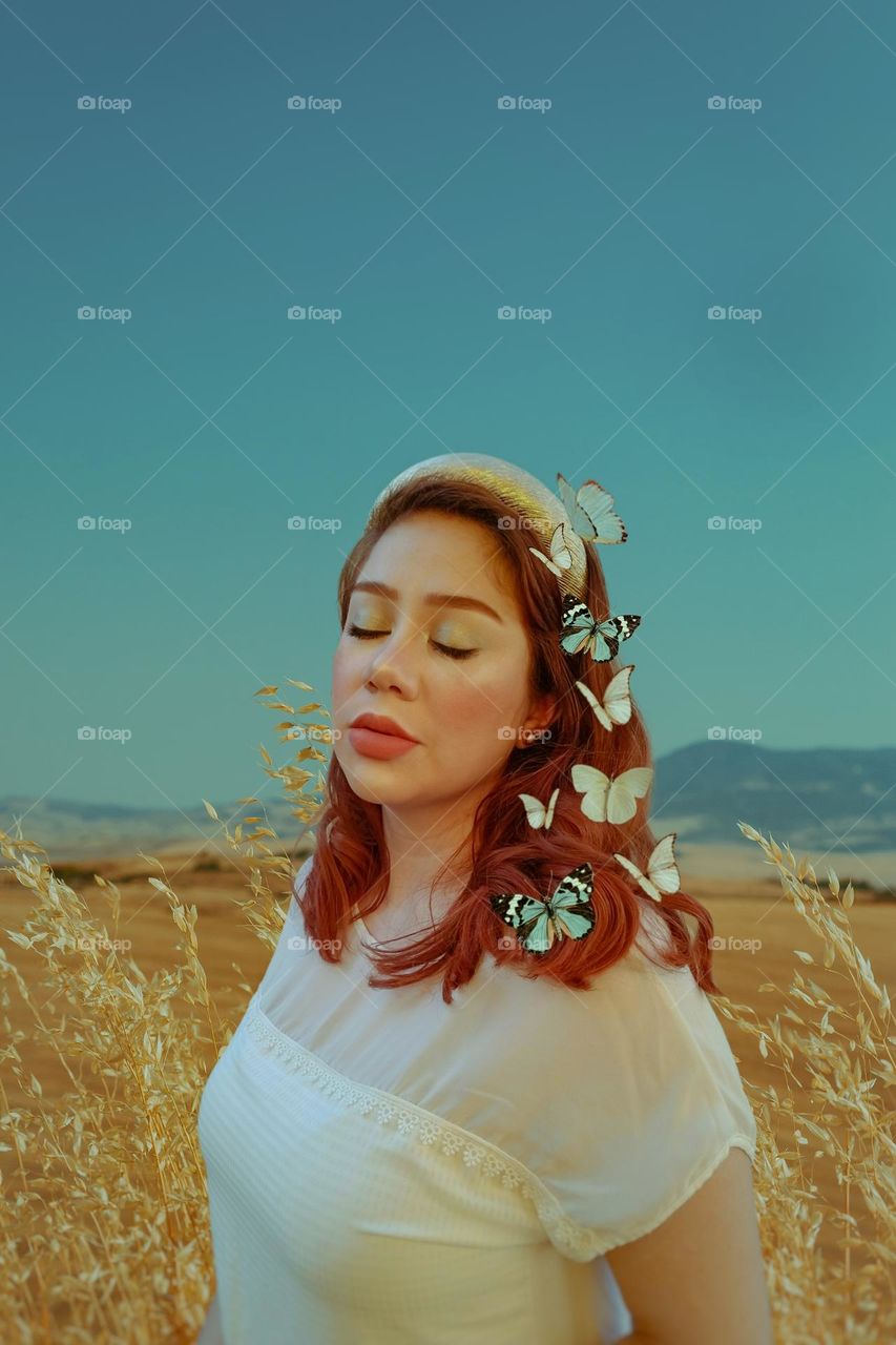 Beautiful woman with red hair and butterflies.