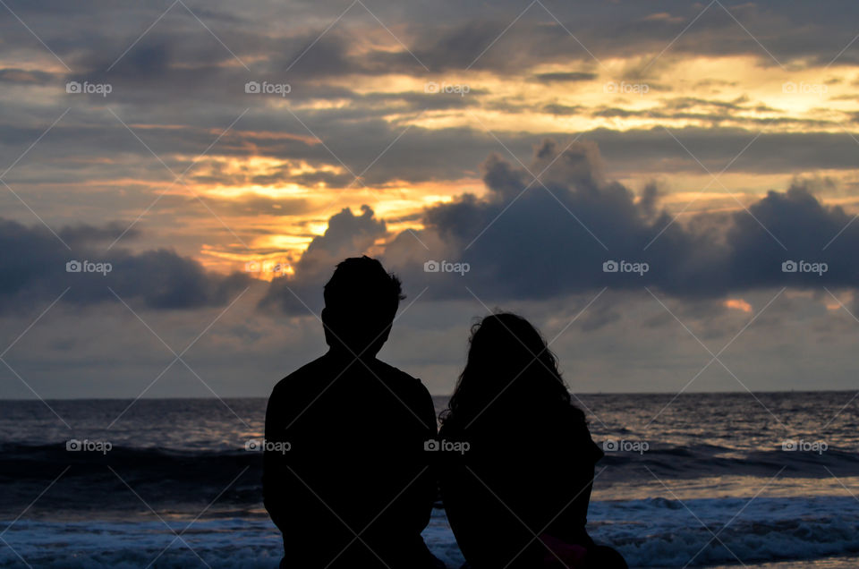 Couple watching beautiful sunset on a beach