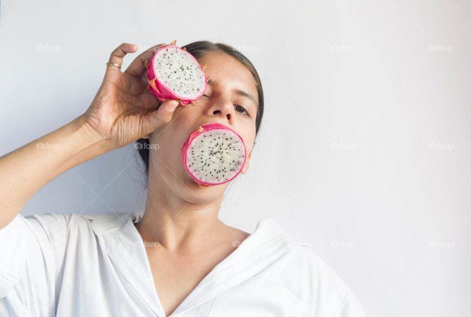 Woman holding dragon fruit in her mouth. Funny moment.