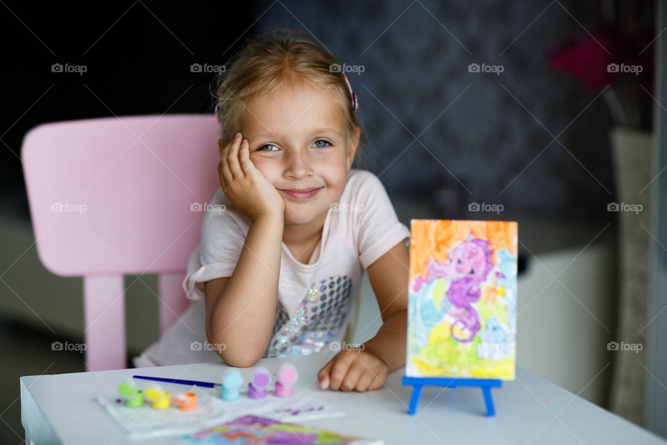 Cute little Caucasian girl with blonde hair sitting at home 