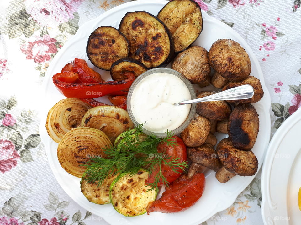 Grilled vegetables on the white plate with a garlic sauce. Vegetarian food. Healthy meal