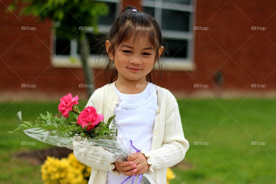 Cute little girl holding bouquet of flowers looking happy