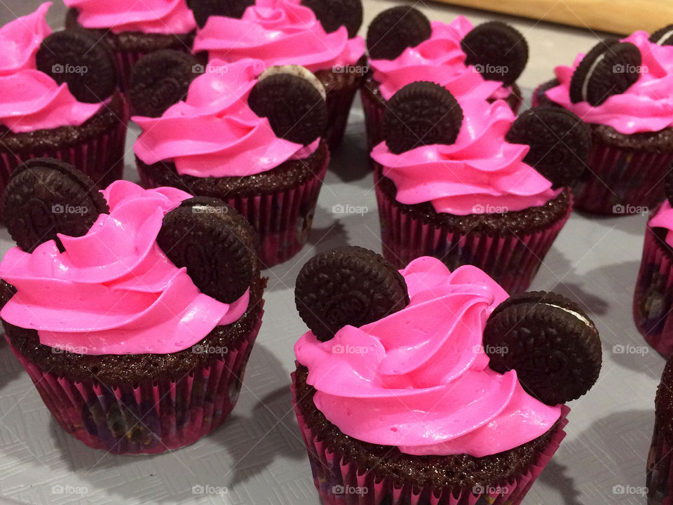 Chocolate cupcakes decorated with neon pink frosting and little cookies ears for a Minnie Mouse themed birthday party 