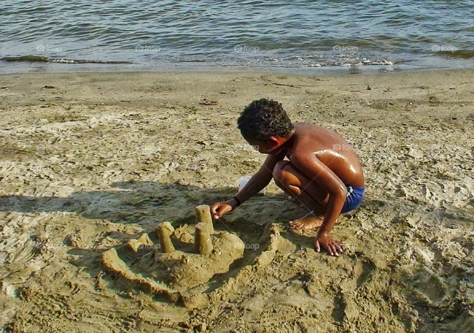 Shirtless boy playing with sand on beach