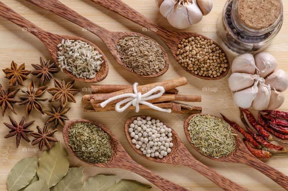 Asian spices on wooden spoons on a chop board 