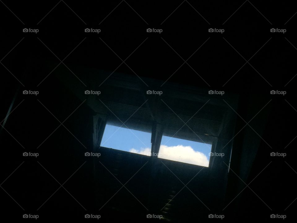 Western clouds drift past patio sky windows and are viewed through a large bedroom window from a pile of pillows. 