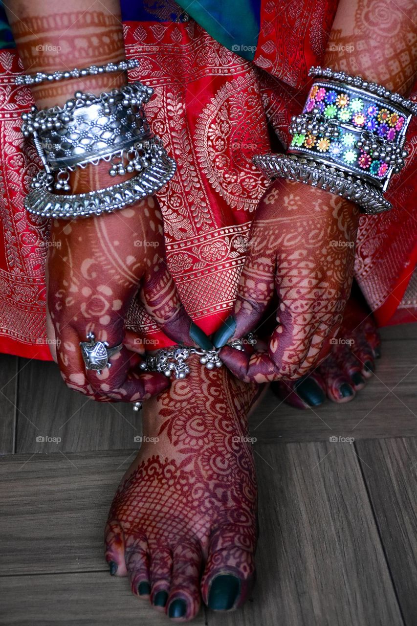 Indian woman wearing traditional saree and jewelry with mehendi in her hands and feet