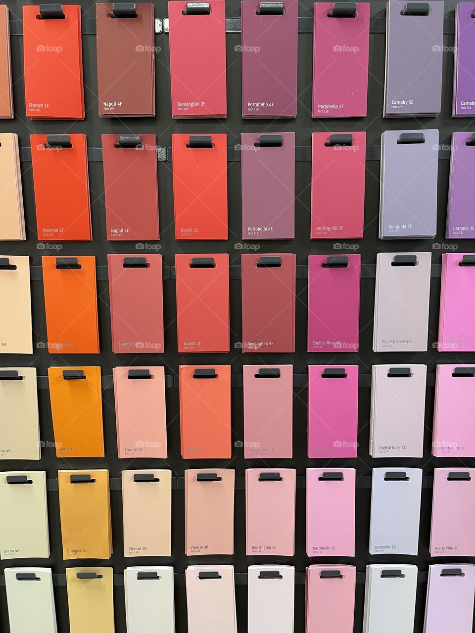 Colorful pantone samples cards set aligned on a wall against dark background, color shades 