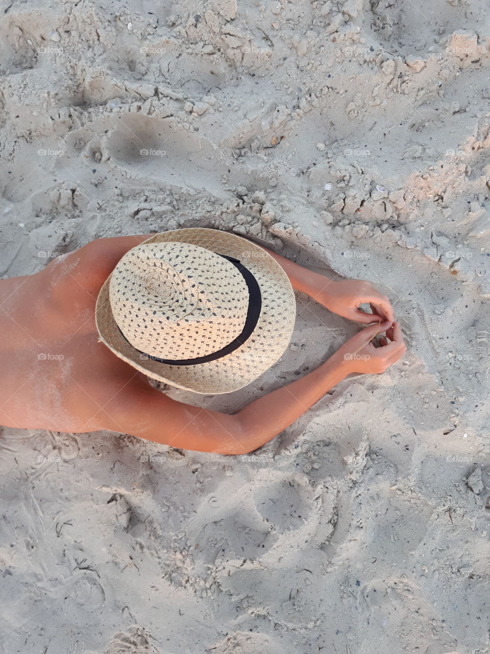 Boy in hat lying at sand