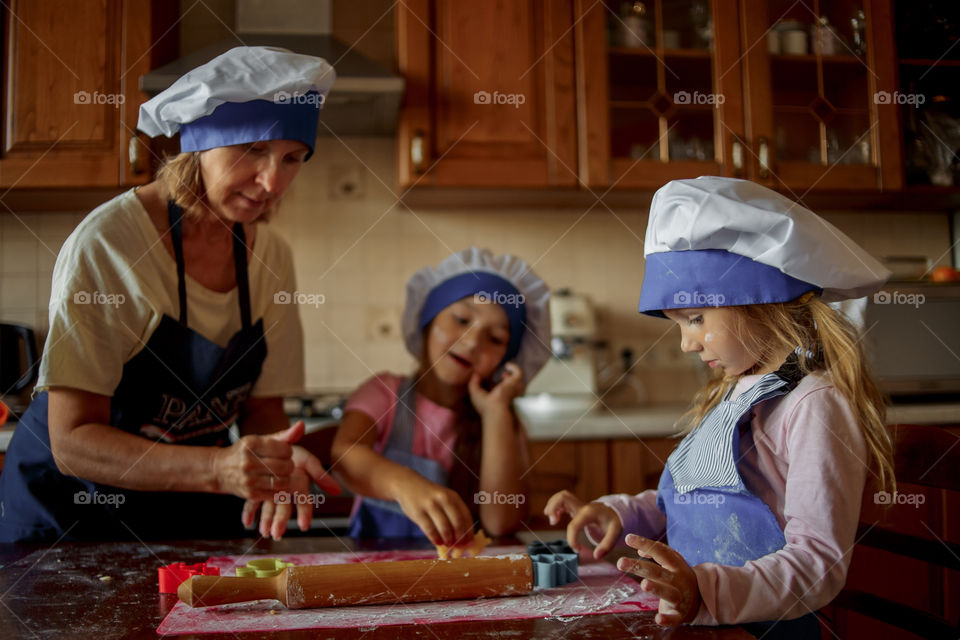 Little sisters with grandma cooking the biscuits 