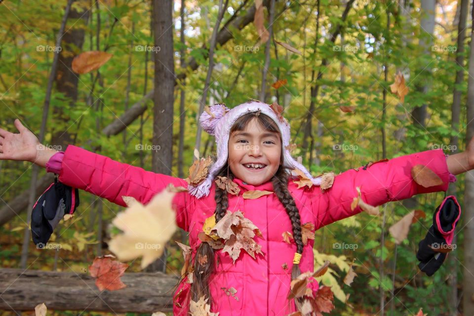 Happy girl is playing with leaves in autumn