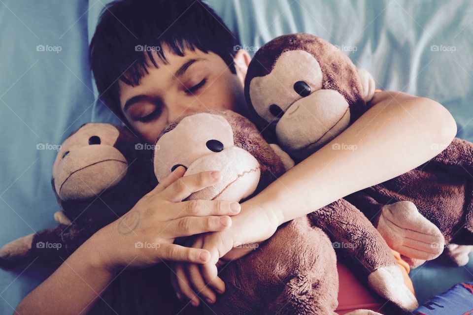 Young boy snuggling with his monkeys while he sleeps