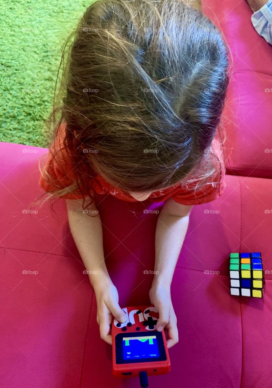 Girl playing with little video games console 