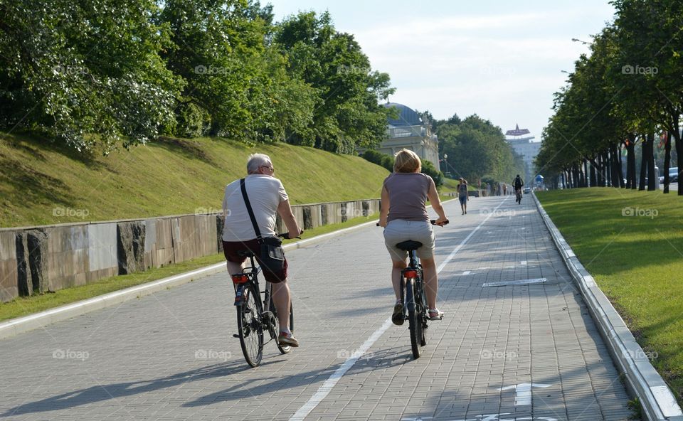 couple ride on a bike streetscape summer time