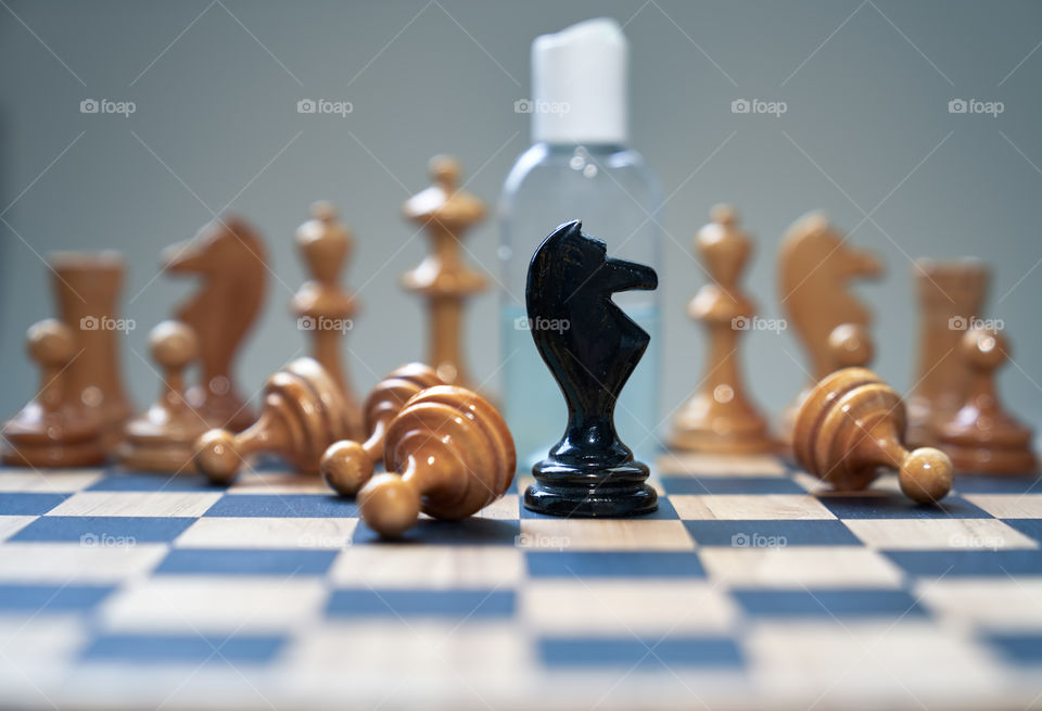 Coronavirus concept image chess pieces and hand sanitizer on chessboard illustrating global struggle against novel covid-19 outbreak.