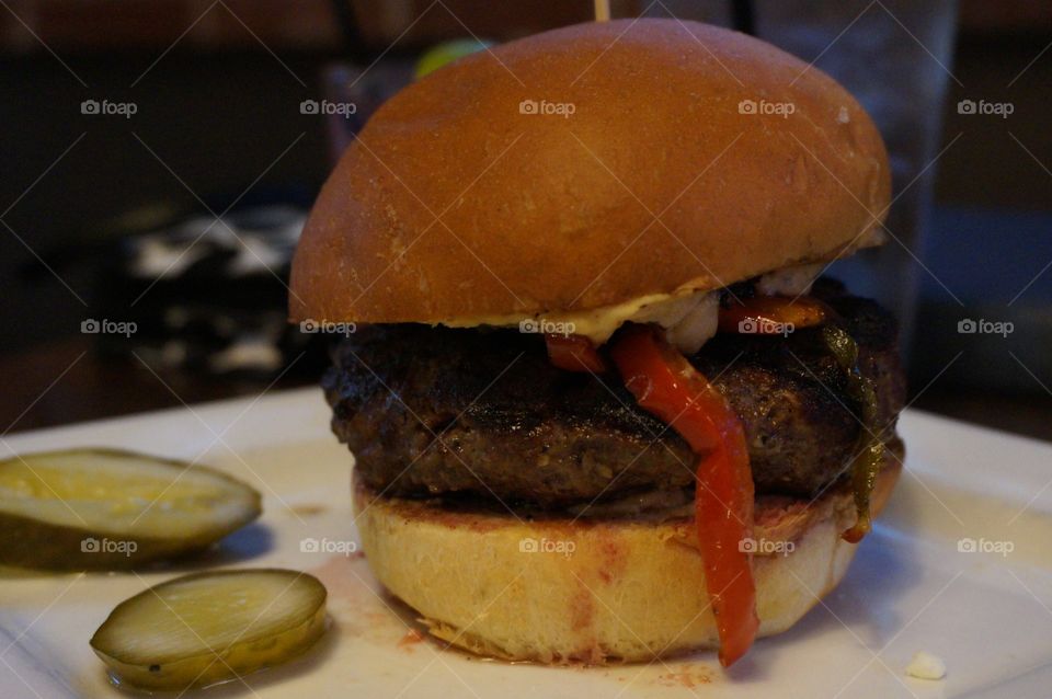 Hamburger with peppers and pickle slices.
