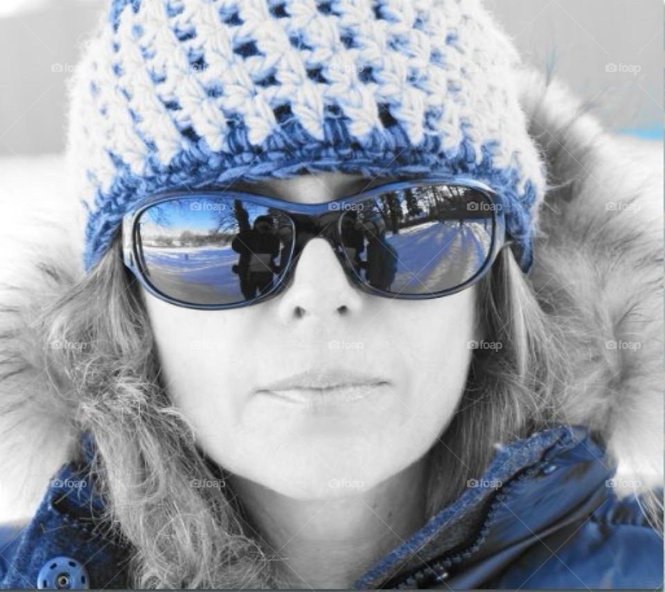 Closeup portrait of a beautiful woman with a knitted hat and sunglasses.