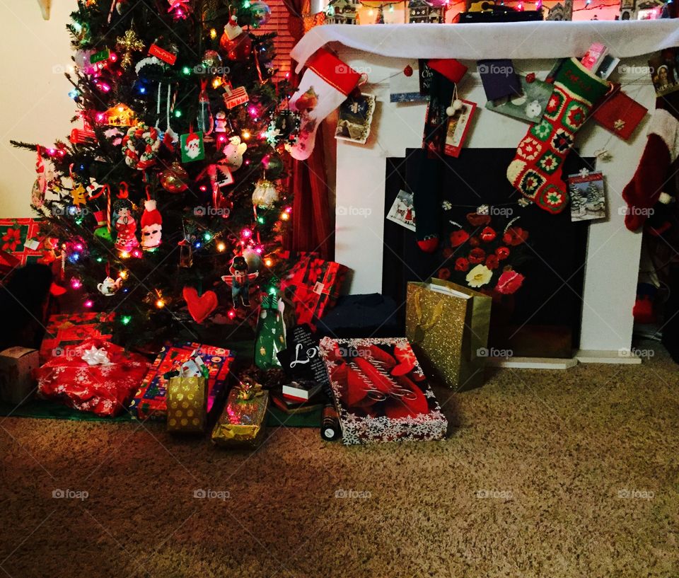 Christmas tree, presents underneath, stockings at the fireplace mantel.