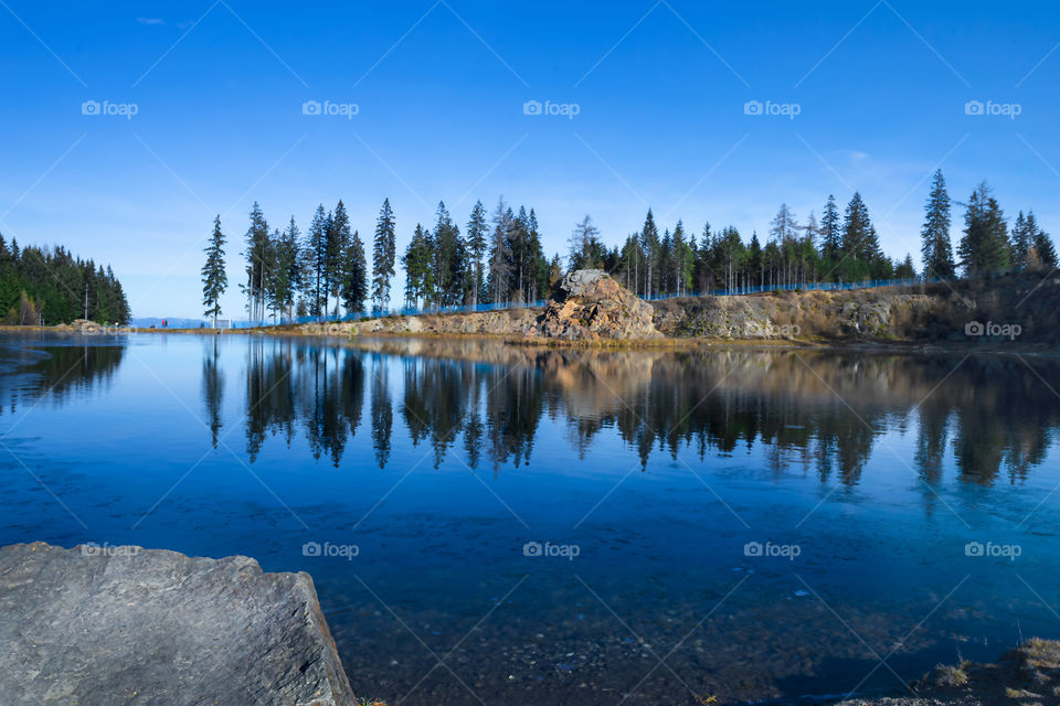 Reflection of the forest in the lake against of the Background the blue sky