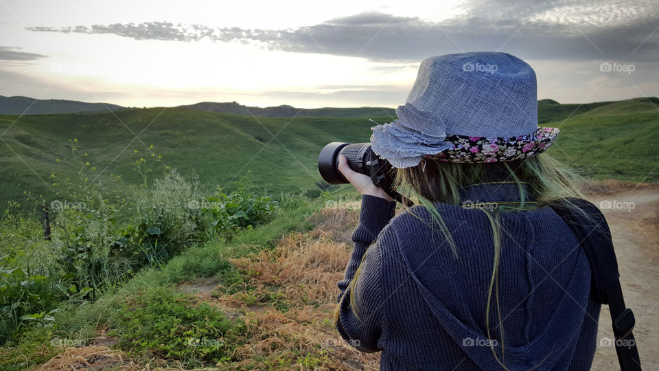 lady holding dslr camera, taking a photo of the hills in spring