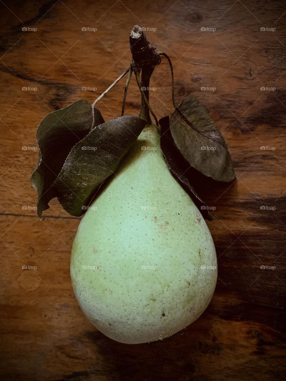 Still life, composition of pear and leaves on old wooden plank