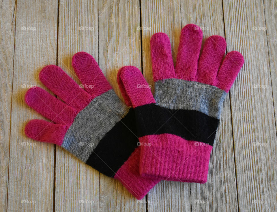 Colorful winter gloves on wood background