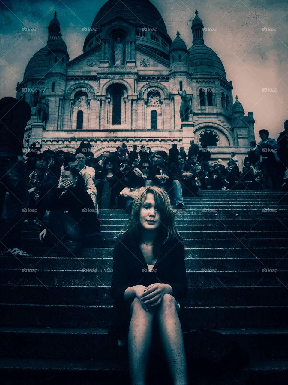 A lonely girl sitting on the stairs in front of Sacre Cour in Paris