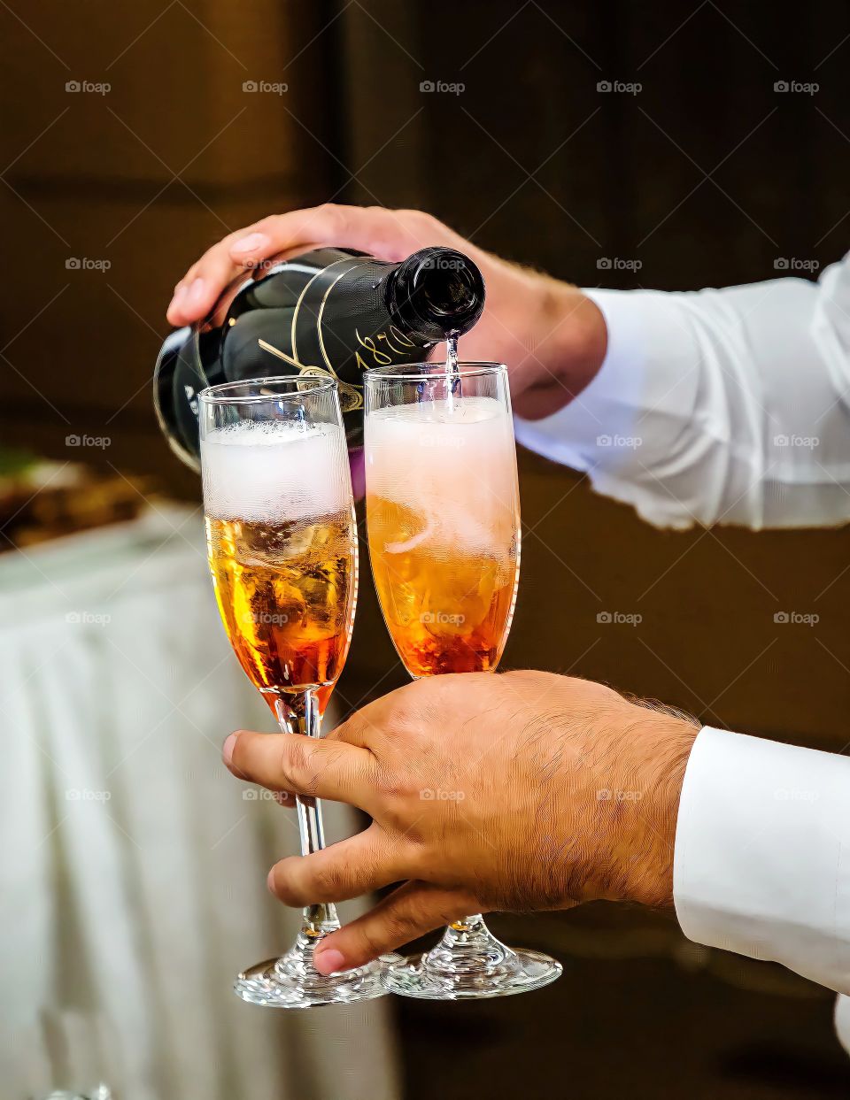 Close up of champagne being poured into glasses
Close up of hand pouring champagne out of the bottle into wine glasses.