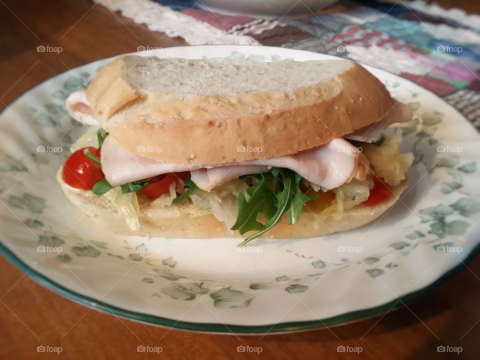 My favorite sandwich is a turkey tomato arugula sauerkraut pickle dijon mustard on cracked whole wheat sour dough on my table at home for lunch