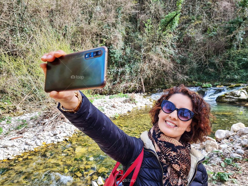 smiling woman uses her smartphone to take a selfie