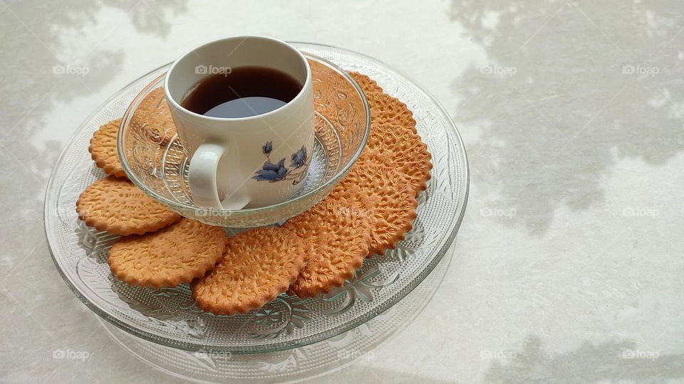 Coffee with biscuits, coffe in a white ceramic glass and biscuits in a transparent glass plate