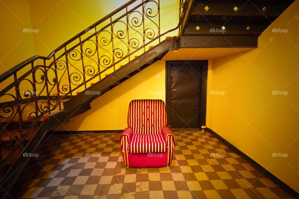 armchair on checker floor in front of stairs