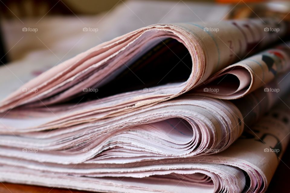 Pile stack folded newspapers closeup on wood office desk, concept business and finance, reading and education, learning and current events, closeup 