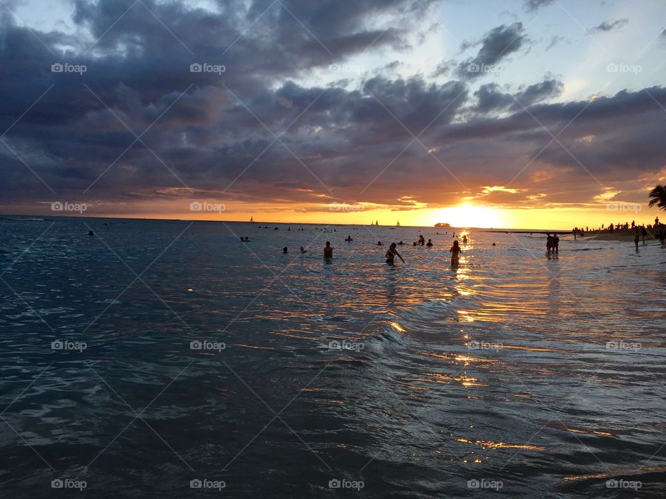 People enjoying at beach during sunset