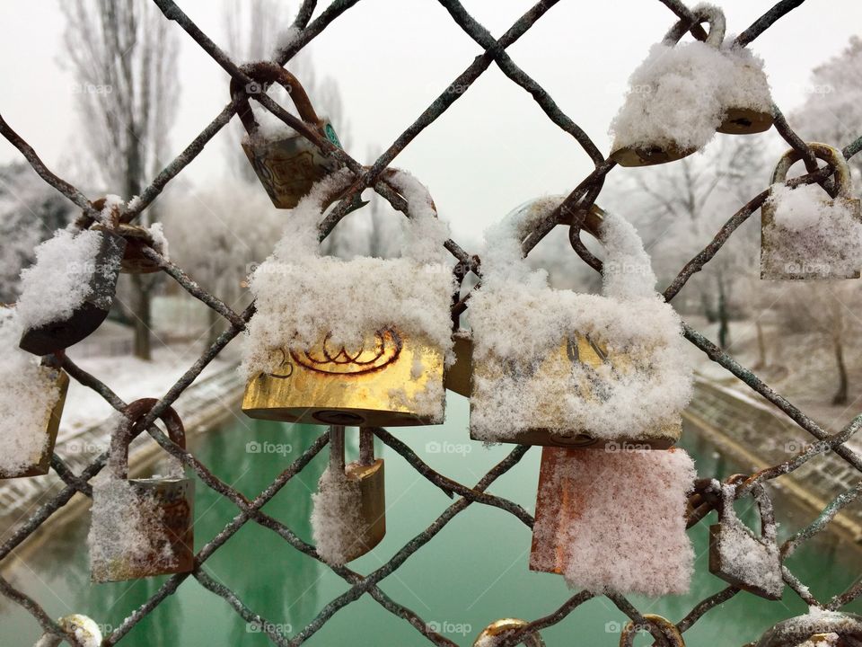 Padlocks covered in snow on the bridge