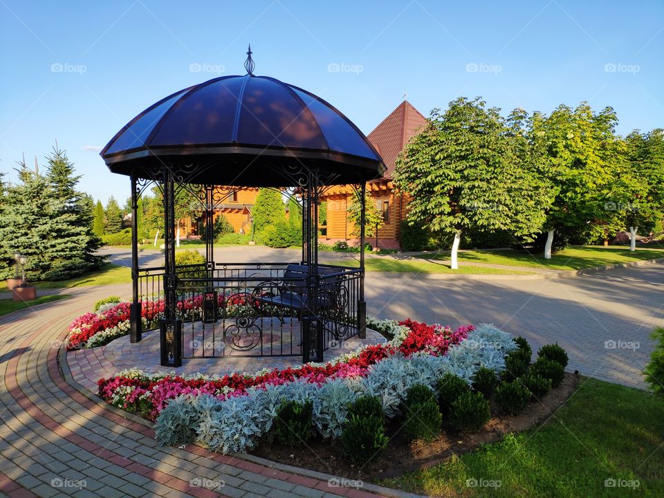 Gazebo in the park among the flower beds