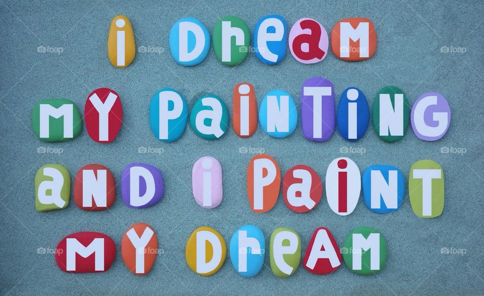 I dream my painting and I paint my dream, Vincent Van Gogh quote composed with multi colored hand painted stone letters over green sand