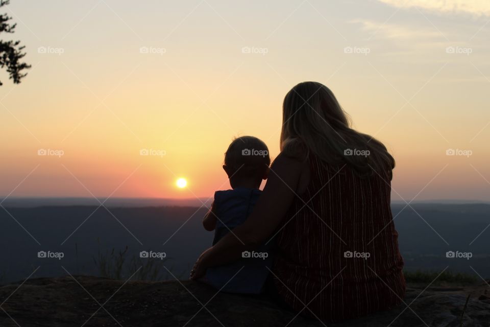 Grandmother and granddaughter watching the sunset on a mountaintop together