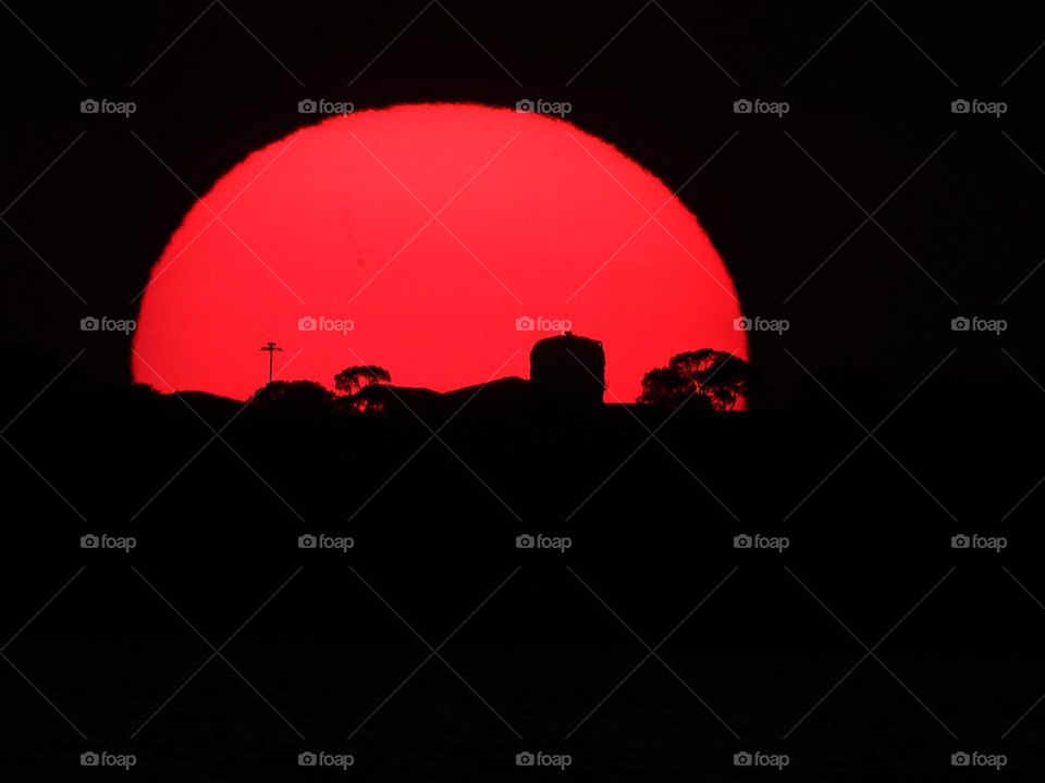 Red descending sunset encompassing a water tower and an array of antennas at Eglin AFB