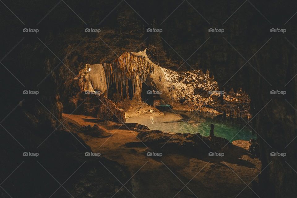 underground cenote with stalactites and stalagmites surrounded by crystal clear waters