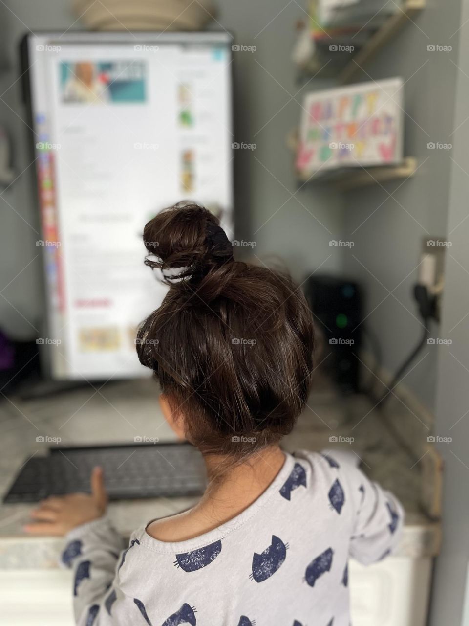 Little girl types on the computer, toddler girl looks for recipes, typing on the computer, toddler looks at computer monitor