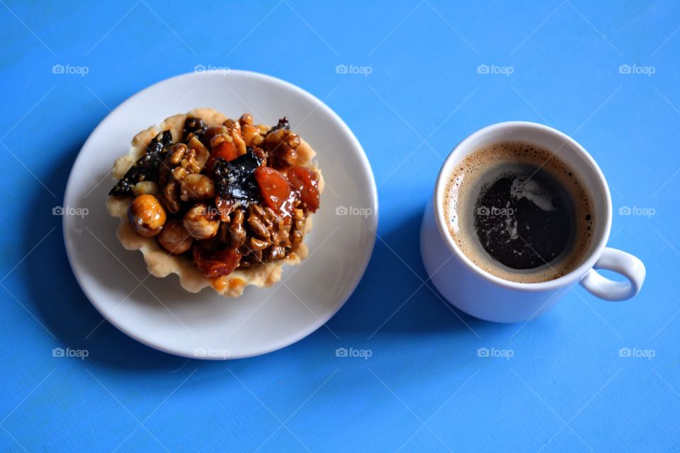 cup of coffee with cupcake on a plate on a blue background, morning routine