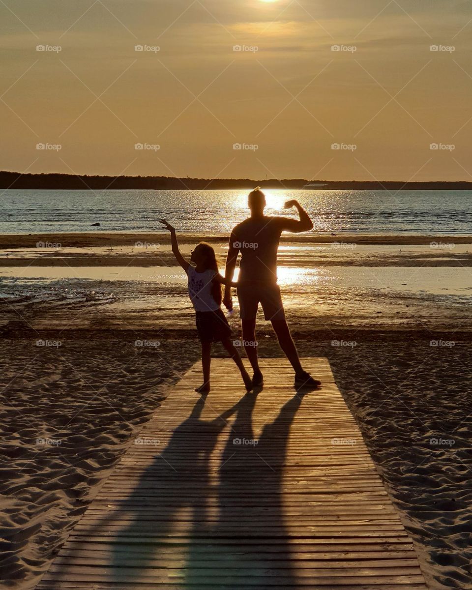 Father and daughter, silhouettes at the seashore 