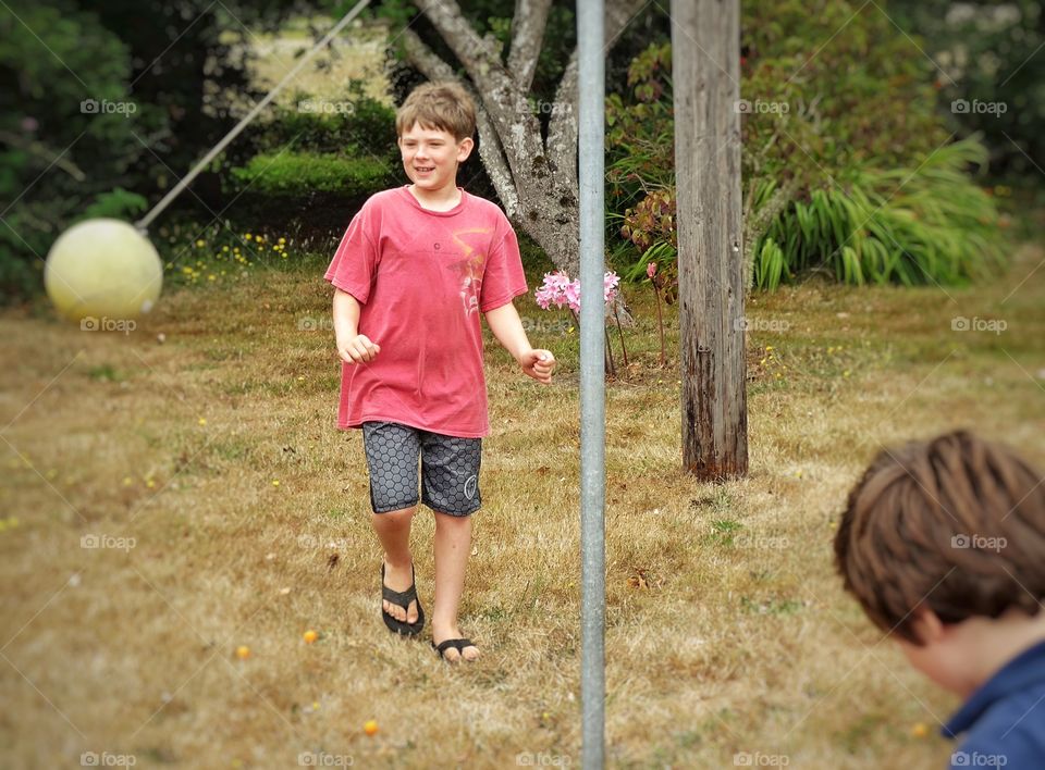 Boys Playing Tetherball. Brothers Knocking Around A Tetherball In The Summertime
