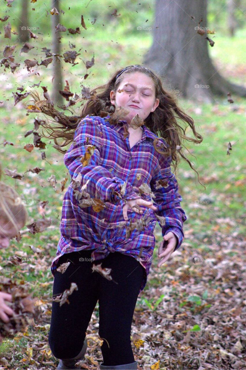 Teenager girl in the park with falling autumn dry leaves