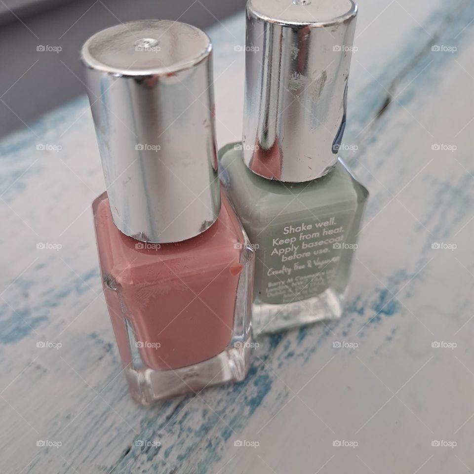 2 bottle of nailvarnish bottles of pink and green on a shabby chic top